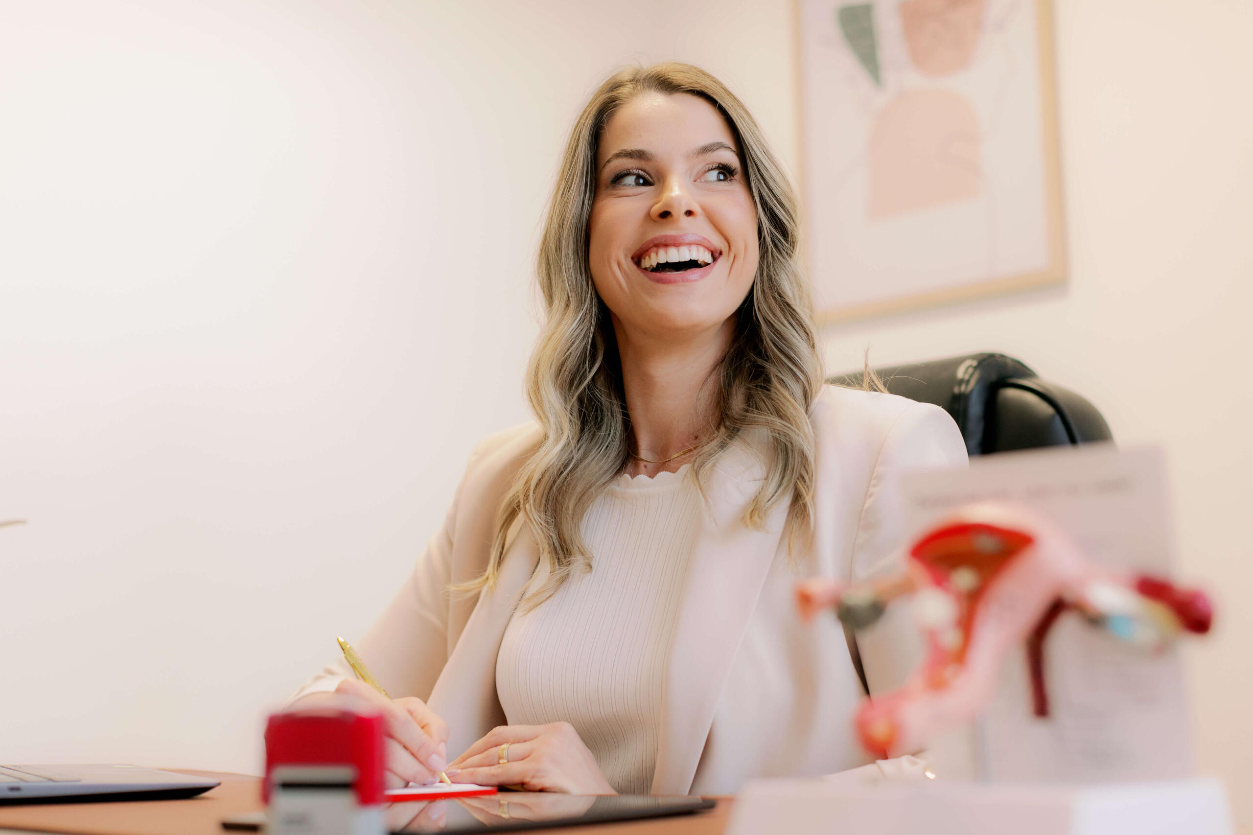 Formação médica em ginecologia e obstetrícia – Dra. Larissa Gianotti Dra. Larissa Gianotti escrevendo em consultório médico, especialista em saúde da mulher